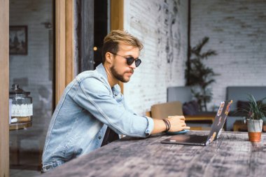 genç çekici iş adamı için bir dizüstü bilgisayar, bir kafe eserlerinde kahve içiyor.