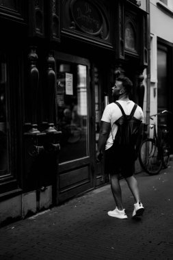 Bir insan bir sırt çantası ile Amsterdam sokaklarında yürüyor.