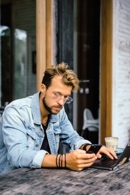 genç çekici iş adamı için bir dizüstü bilgisayar, bir kafe eserlerinde kahve içiyor.
