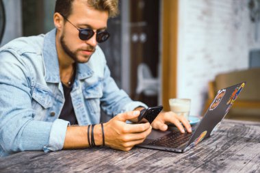 genç çekici iş adamı için bir dizüstü bilgisayar, bir kafe eserlerinde kahve içiyor.