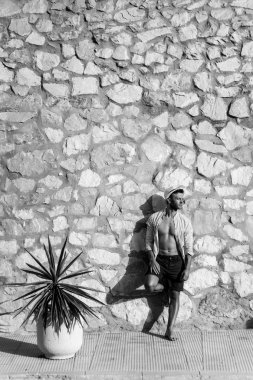 çizgili gömlekli, hasır şapka giyen bir adam, küçük bir İspanyol kasabasının sokaklarında yürüyor..