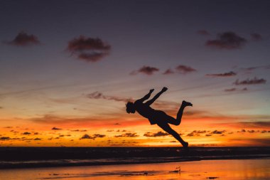 insanlar gün batımında okyanus kıyısında. adam batan güneşin fonunda atlar.