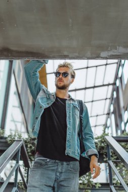 tropikal bir yerde, palmiye ağaçları ve yeşil, güneş gözlüklü bir arka plan üzerinde poz genç çekici adam