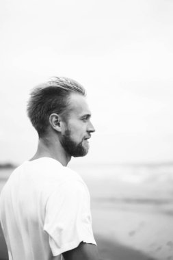 okyanus plaj boyunca kumlu bir plaj üzerinde yürüyen genç çekici adam