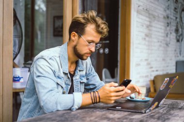 genç çekici iş adamı için bir dizüstü bilgisayar, bir kafe eserlerinde kahve içiyor.