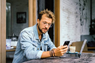 genç çekici iş adamı için bir dizüstü bilgisayar, bir kafe eserlerinde kahve içiyor.