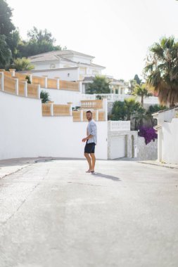 çizgili gömlekli, hasır şapka giyen bir adam, küçük bir İspanyol kasabasının sokaklarında yürüyor..