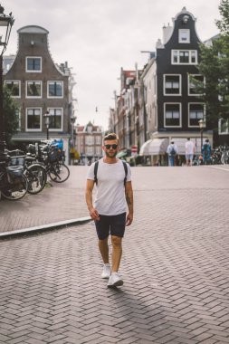 Bir insan bir sırt çantası ile Amsterdam sokaklarında yürüyor.