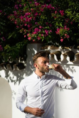 Beyaz gömlekli adam yazın açık havada kahve içer.