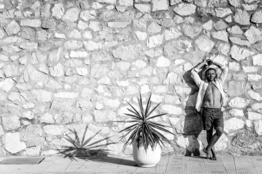 çizgili gömlekli, hasır şapka giyen bir adam, küçük bir İspanyol kasabasının sokaklarında yürüyor..