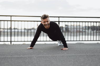 Yakışıklı atletik genç adam dışarıda egzersiz yapıyor.