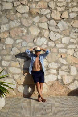 çizgili gömlekli, hasır şapka giyen bir adam, küçük bir İspanyol kasabasının sokaklarında yürüyor..