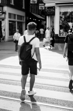 Bir insan bir sırt çantası ile Amsterdam sokaklarında yürüyor.