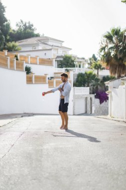 çizgili gömlekli, hasır şapka giyen bir adam, küçük bir İspanyol kasabasının sokaklarında yürüyor..