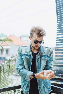 tropikal bir yerde, palmiye ağaçları ve yeşil, güneş gözlüklü bir arka plan üzerinde poz genç çekici adam