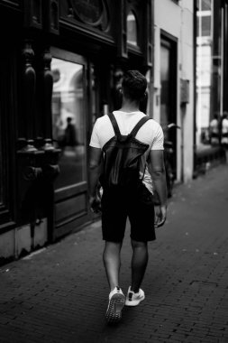 Bir insan bir sırt çantası ile Amsterdam sokaklarında yürüyor.