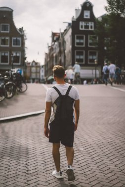 Bir insan bir sırt çantası ile Amsterdam sokaklarında yürüyor.