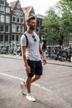 Bir insan bir sırt çantası ile Amsterdam sokaklarında yürüyor.