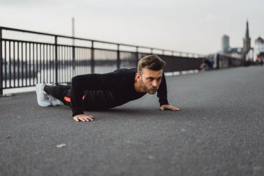 Yakışıklı atletik genç adam dışarıda egzersiz yapıyor.