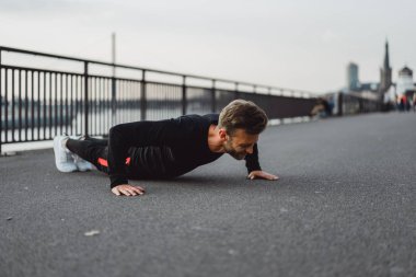 Yakışıklı atletik genç adam dışarıda egzersiz yapıyor.