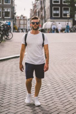 Bir insan bir sırt çantası ile Amsterdam sokaklarında yürüyor.