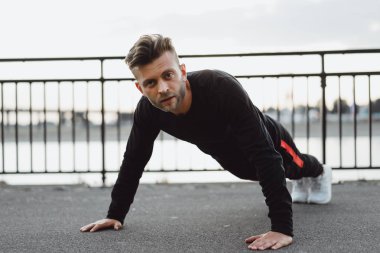 Yakışıklı atletik genç adam dışarıda egzersiz yapıyor.