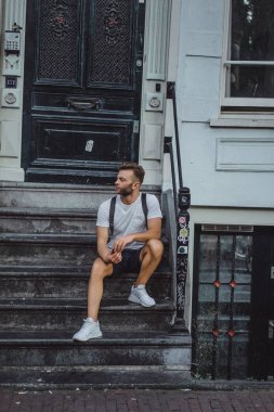 Bir insan bir sırt çantası ile Amsterdam sokaklarında yürüyor.