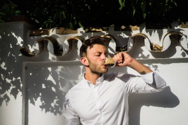 Beyaz gömlekli adam yazın açık havada kahve içer.