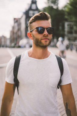 Bir insan bir sırt çantası ile Amsterdam sokaklarında yürüyor.