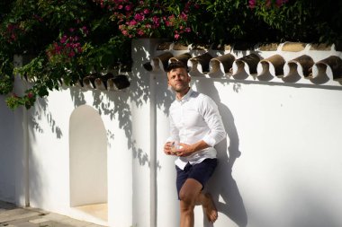 Beyaz gömlekli adam yazın açık havada kahve içer.