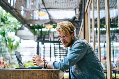 genç çekici iş adamı için bir dizüstü bilgisayar, bir kafe eserlerinde kahve içiyor.