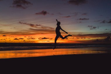 insanlar gün batımında okyanus kıyısında. adam batan güneşin fonunda atlar.