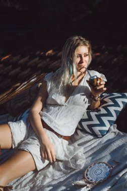 Çatıda mate çay içme uzun sarı saçlı güzel Hint hippi kız. Calabaza