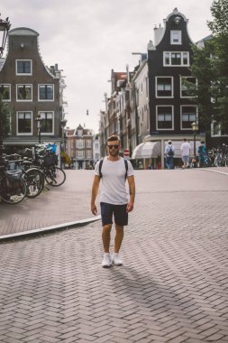 Bir insan bir sırt çantası ile Amsterdam sokaklarında yürüyor.