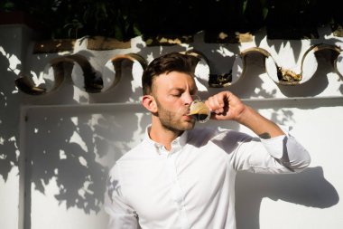 Beyaz gömlekli adam yazın açık havada kahve içer.