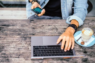 genç çekici iş adamı için bir dizüstü bilgisayar, bir kafe eserlerinde kahve içiyor.