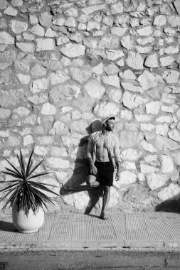 çizgili gömlekli, hasır şapka giyen bir adam, küçük bir İspanyol kasabasının sokaklarında yürüyor..