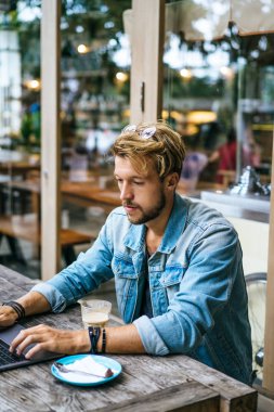 genç çekici iş adamı için bir dizüstü bilgisayar, bir kafe eserlerinde kahve içiyor.