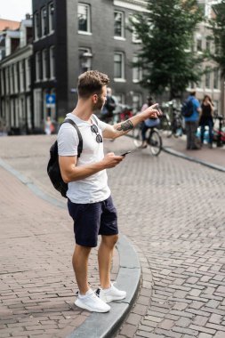 Bir insan bir sırt çantası ile Amsterdam sokaklarında yürüyor.