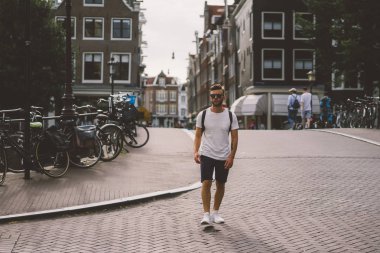 Bir insan bir sırt çantası ile Amsterdam sokaklarında yürüyor.