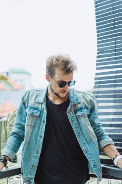 tropikal bir yerde, palmiye ağaçları ve yeşil, güneş gözlüklü bir arka plan üzerinde poz genç çekici adam