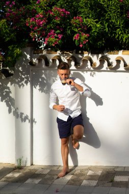 Beyaz gömlekli adam yazın açık havada kahve içer.