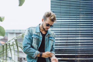 tropikal bir yerde, palmiye ağaçları ve yeşil, güneş gözlüklü bir arka plan üzerinde poz genç çekici adam