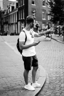 Bir insan bir sırt çantası ile Amsterdam sokaklarında yürüyor.