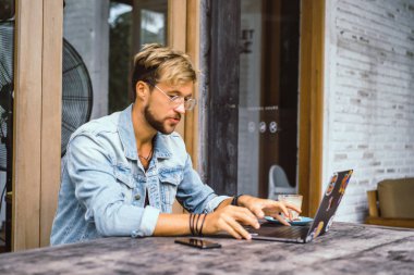 genç çekici iş adamı için bir dizüstü bilgisayar, bir kafe eserlerinde kahve içiyor.