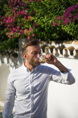 Beyaz gömlekli adam yazın açık havada kahve içer.