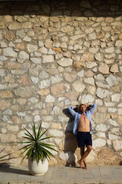 çizgili gömlekli, hasır şapka giyen bir adam, küçük bir İspanyol kasabasının sokaklarında yürüyor..