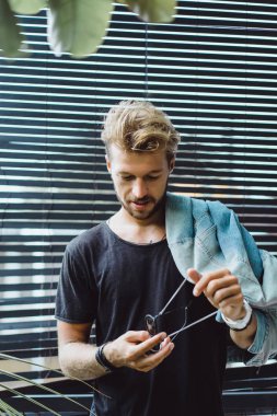 tropikal bir yerde, palmiye ağaçları ve yeşil, güneş gözlüklü bir arka plan üzerinde poz genç çekici adam