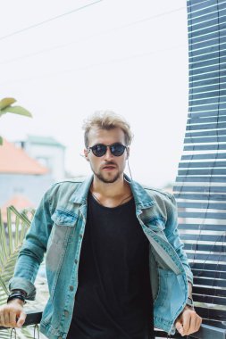 tropikal bir yerde, palmiye ağaçları ve yeşil, güneş gözlüklü bir arka plan üzerinde poz genç çekici adam