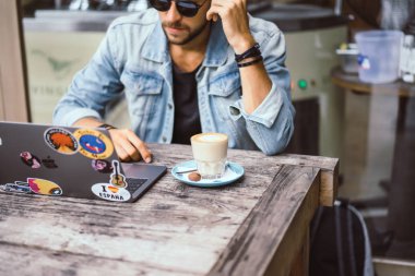 genç çekici iş adamı için bir dizüstü bilgisayar, bir kafe eserlerinde kahve içiyor.